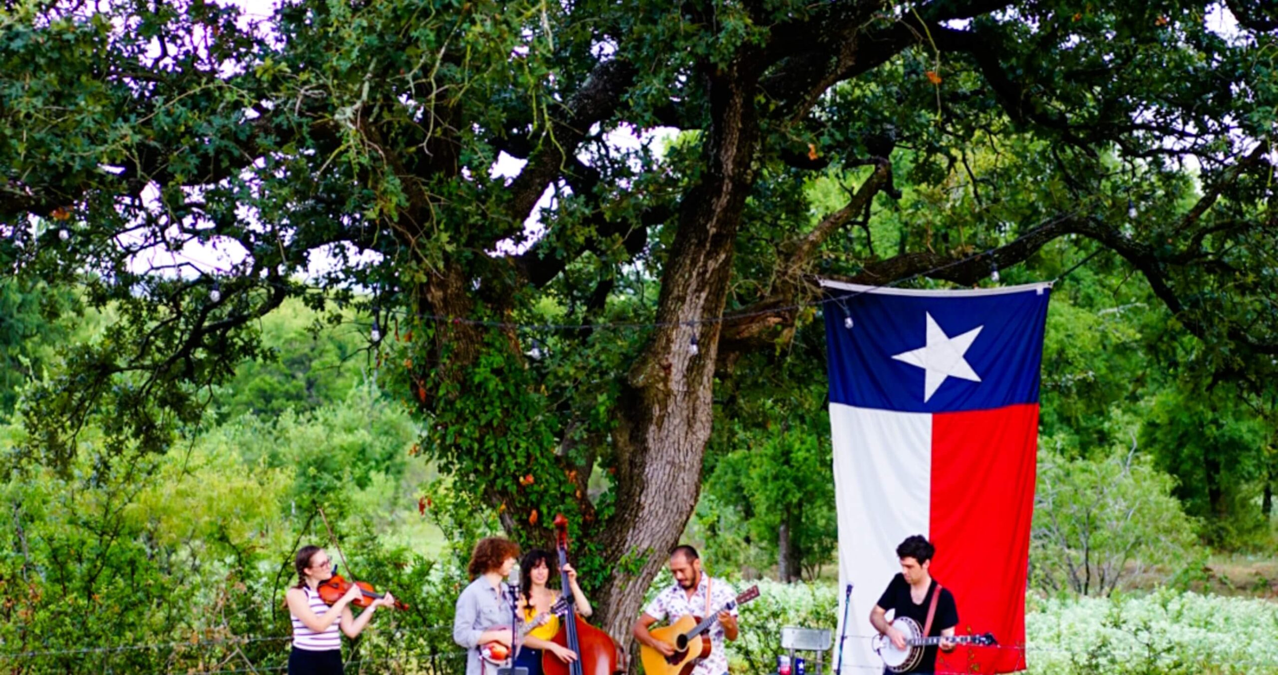 A group of people playing instruments under a flag in a family-friendly neighborhood.