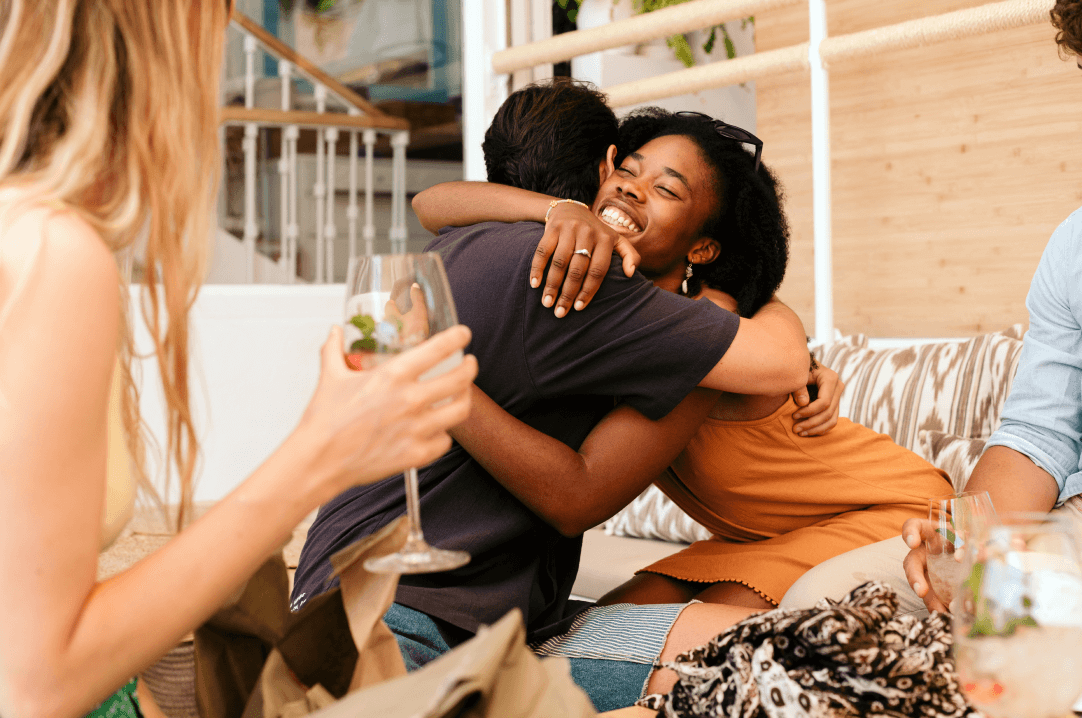 Two people embracing with smiles, surrounded by friends at a social gathering in one of the new home communities in Mansfield TX.