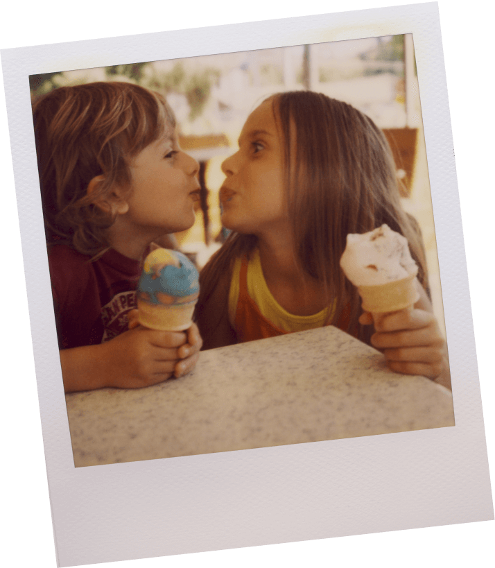 Two children holding ice cream cones in their new home in Goodland TX appear to exchange a playful kiss.