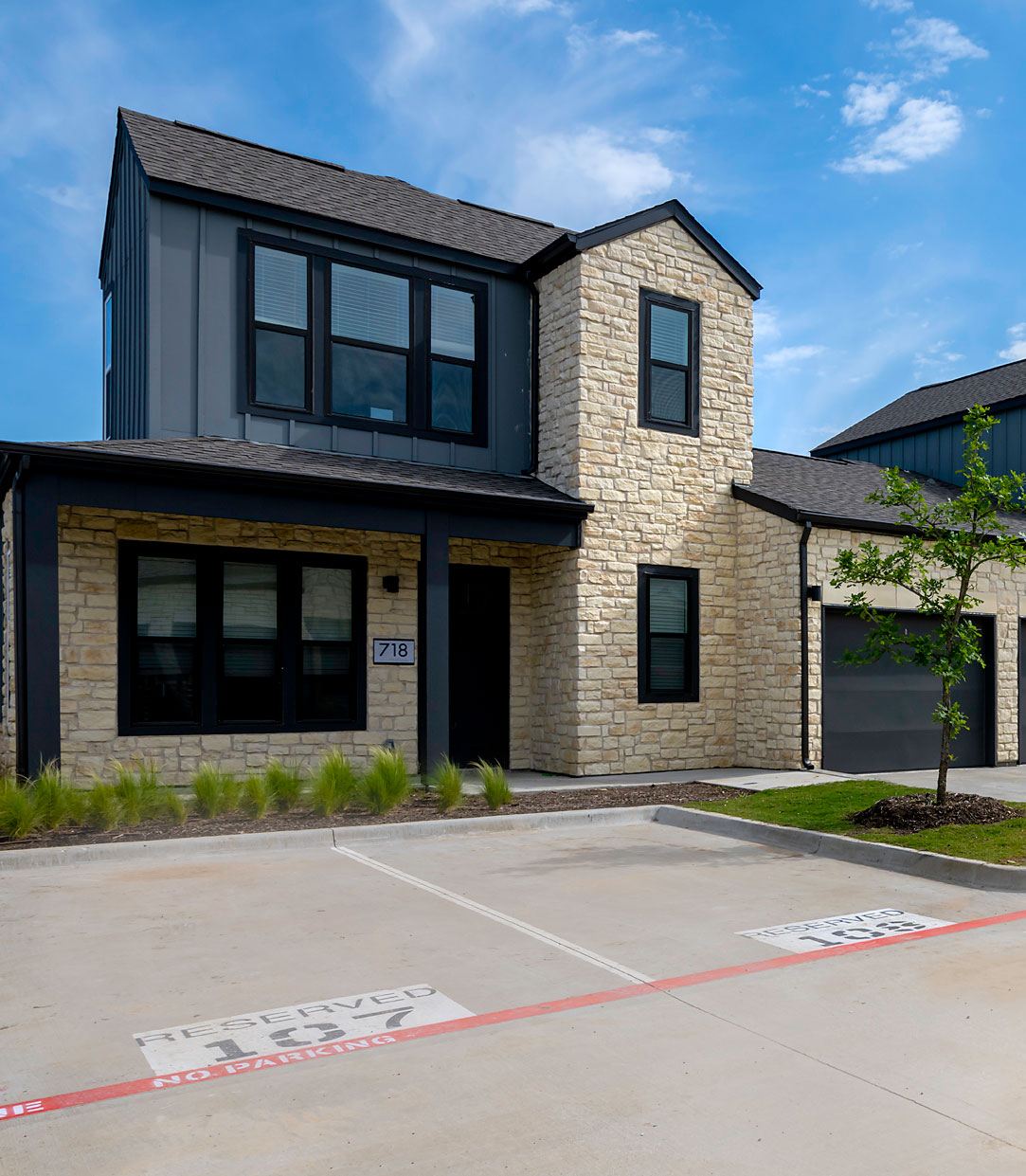 Modern two-story house with stone facade and designated parking spaces in new home communities in Mansfield, TX.