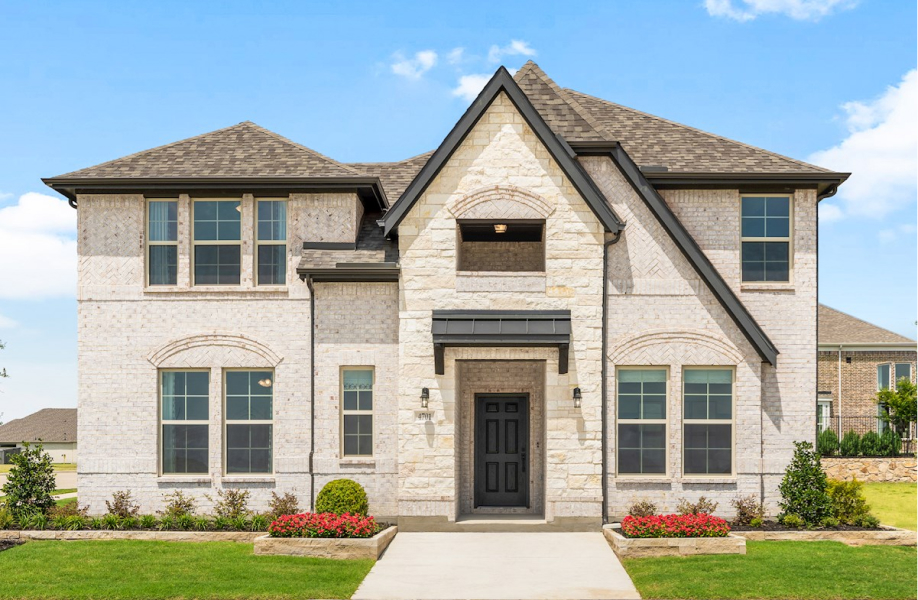 New two-story suburban house in Mansfield TX with a stone facade and landscaped front yard.