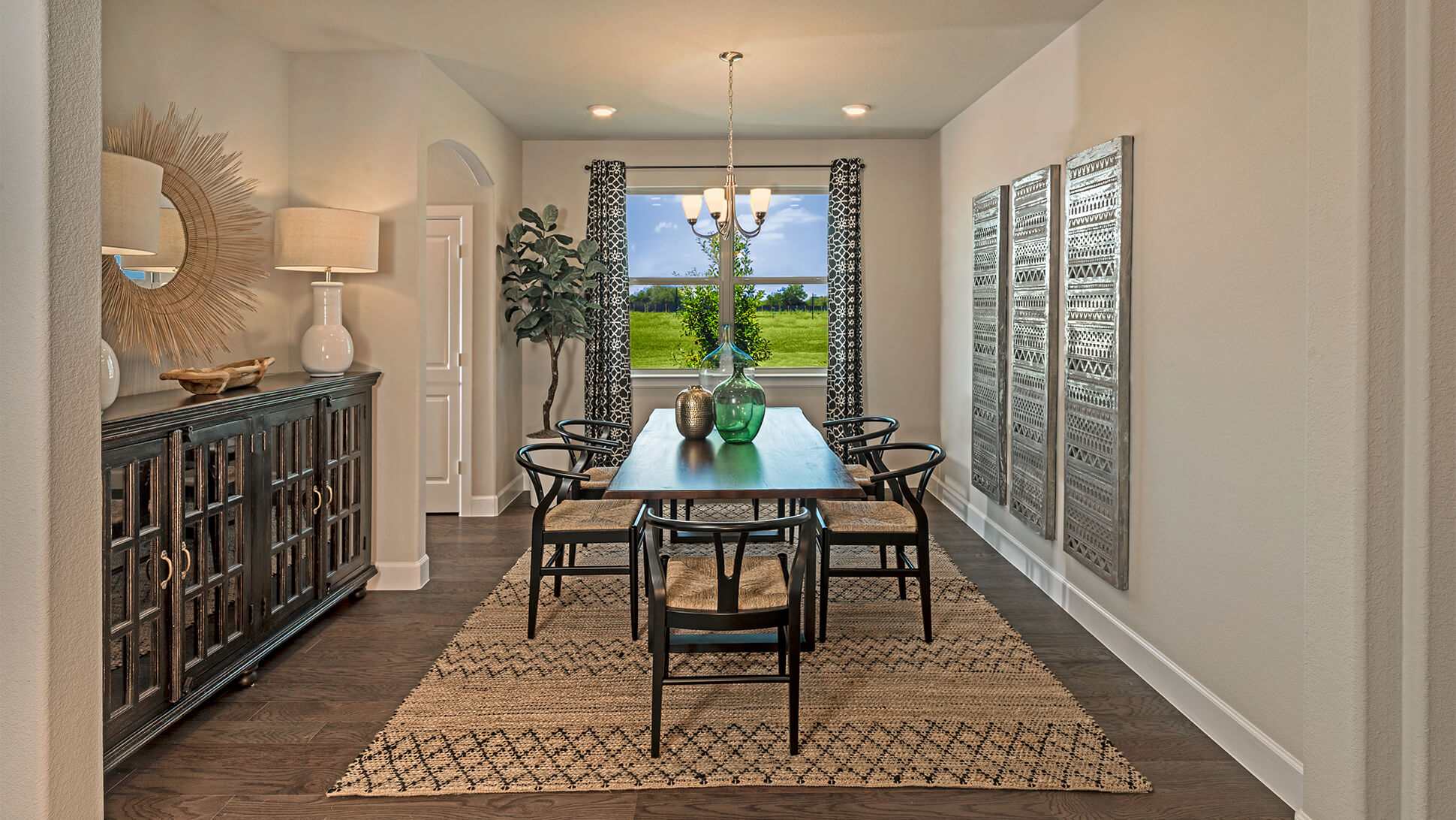 Modern dining room with a wooden table, black chairs, and a view of the garden through large windows in new homes in Mansfield TX.