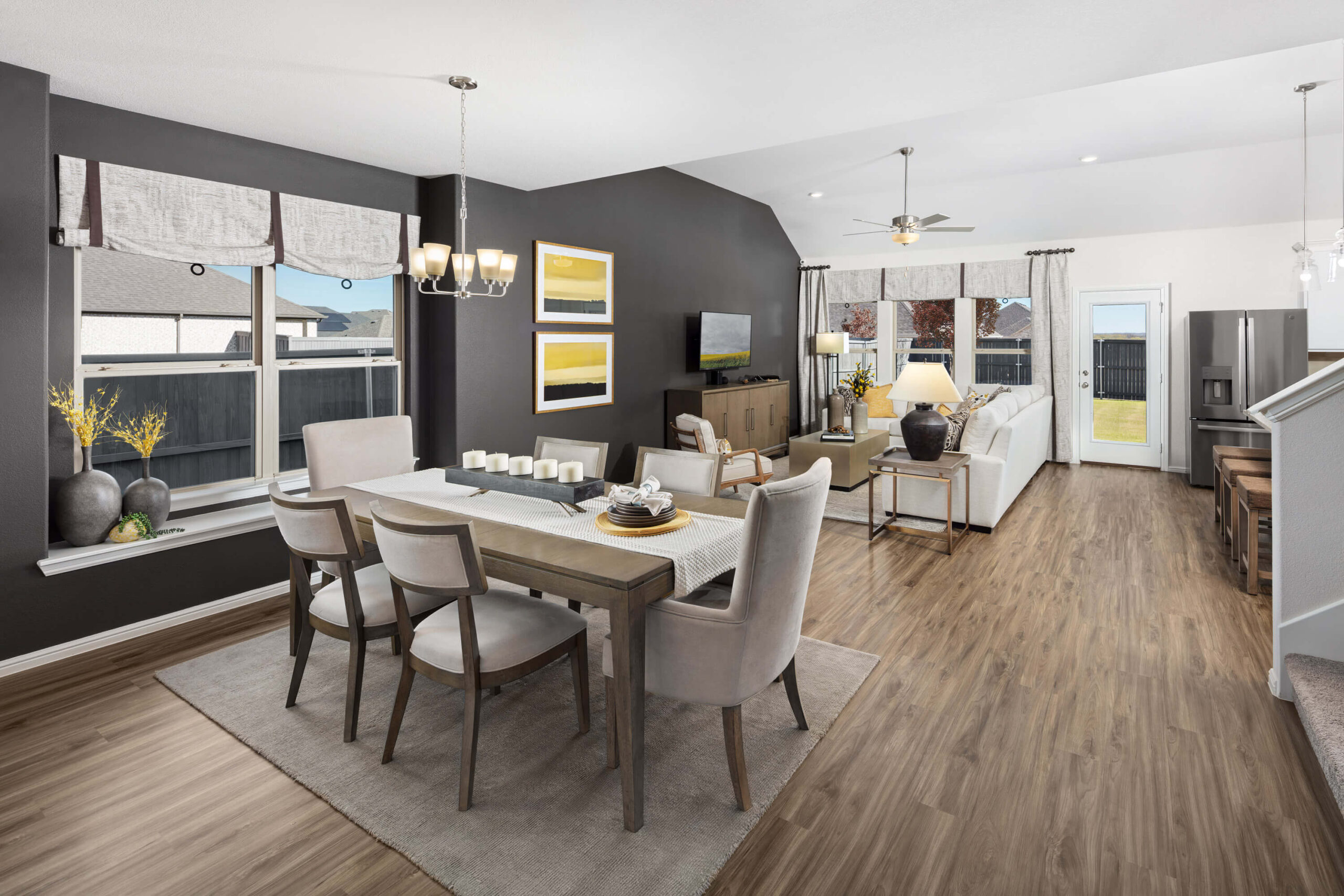 Modern dining and living area with an open floor plan, neutral tones, and pops of yellow accents in new home communities in Mansfield TX.