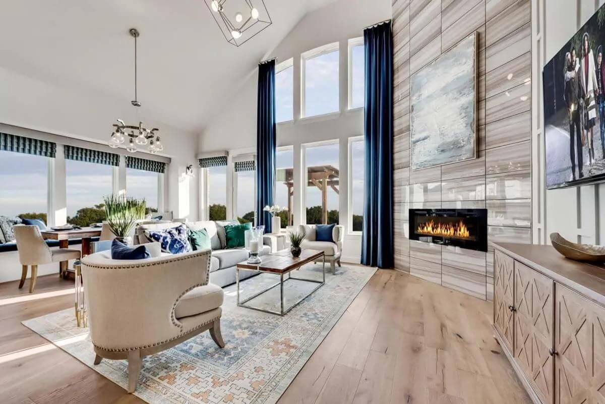 A bright, modern living room in new homes in DFW with high ceilings, large windows, a fireplace, and contemporary furnishings.