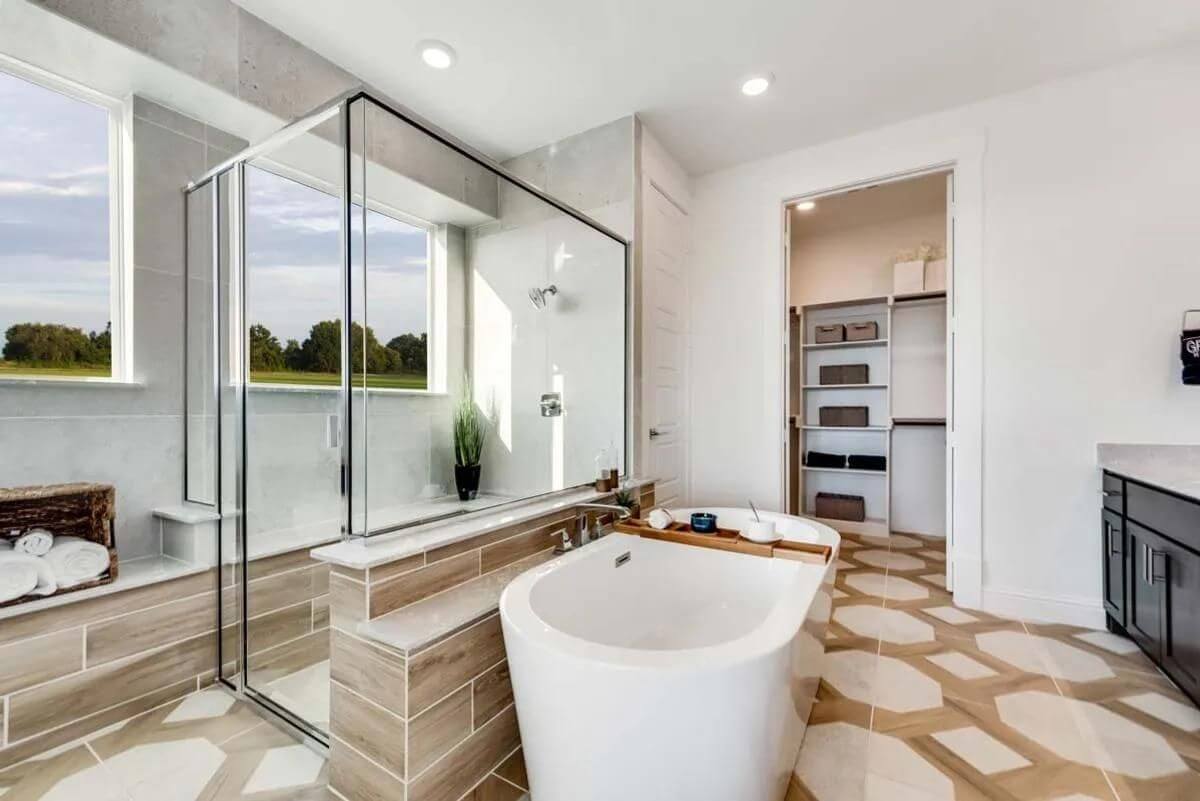 Modern bathroom interior with a freestanding tub, glass-enclosed shower, and dual vanities, designed by new home builders in Mansfield TX.