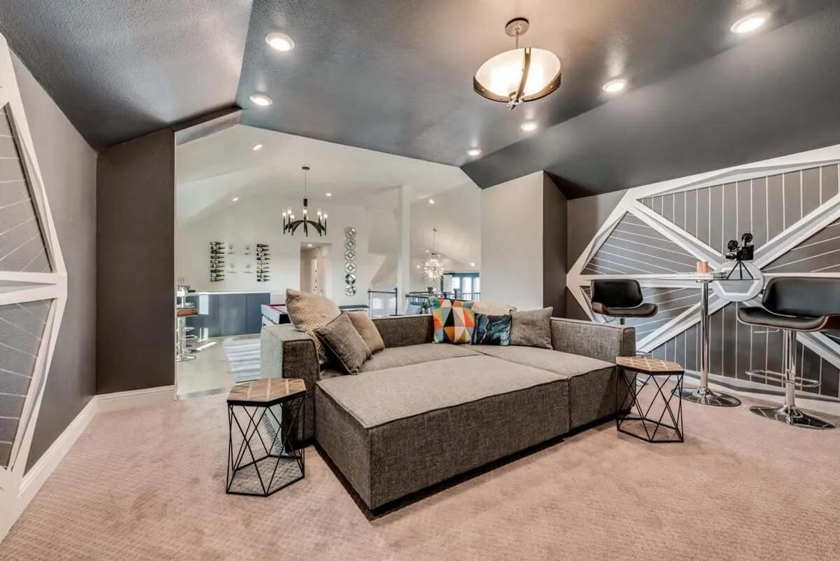 Modern living room with a sectional sofa, beige carpet, dark ceiling, and an open concept layout leading to a kitchen and dining area in new homes in DFW.