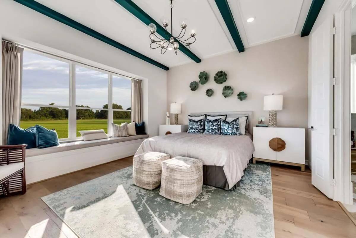 A bright and spacious bedroom in new homes in DFW with a large bed, hardwood floors, and a view of the green landscape outside.