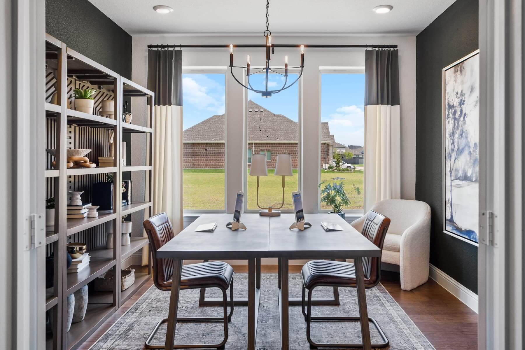 Modern dining room with a wooden table, upholstered chairs, and a view of the backyard in new homes in Mansfield TX.