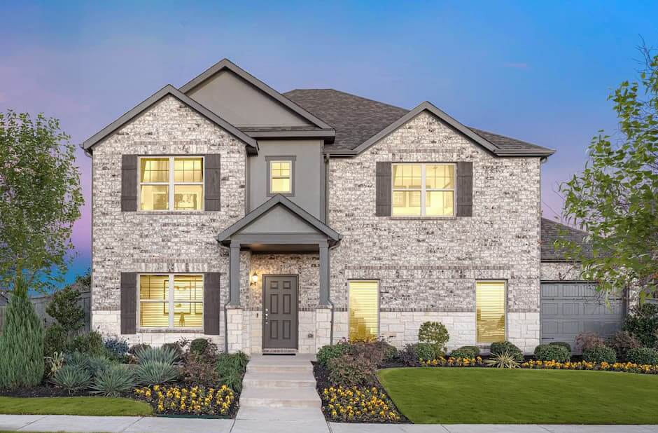 Modern two-story brick house with landscaped yard at twilight in new home communities in Mansfield, TX.