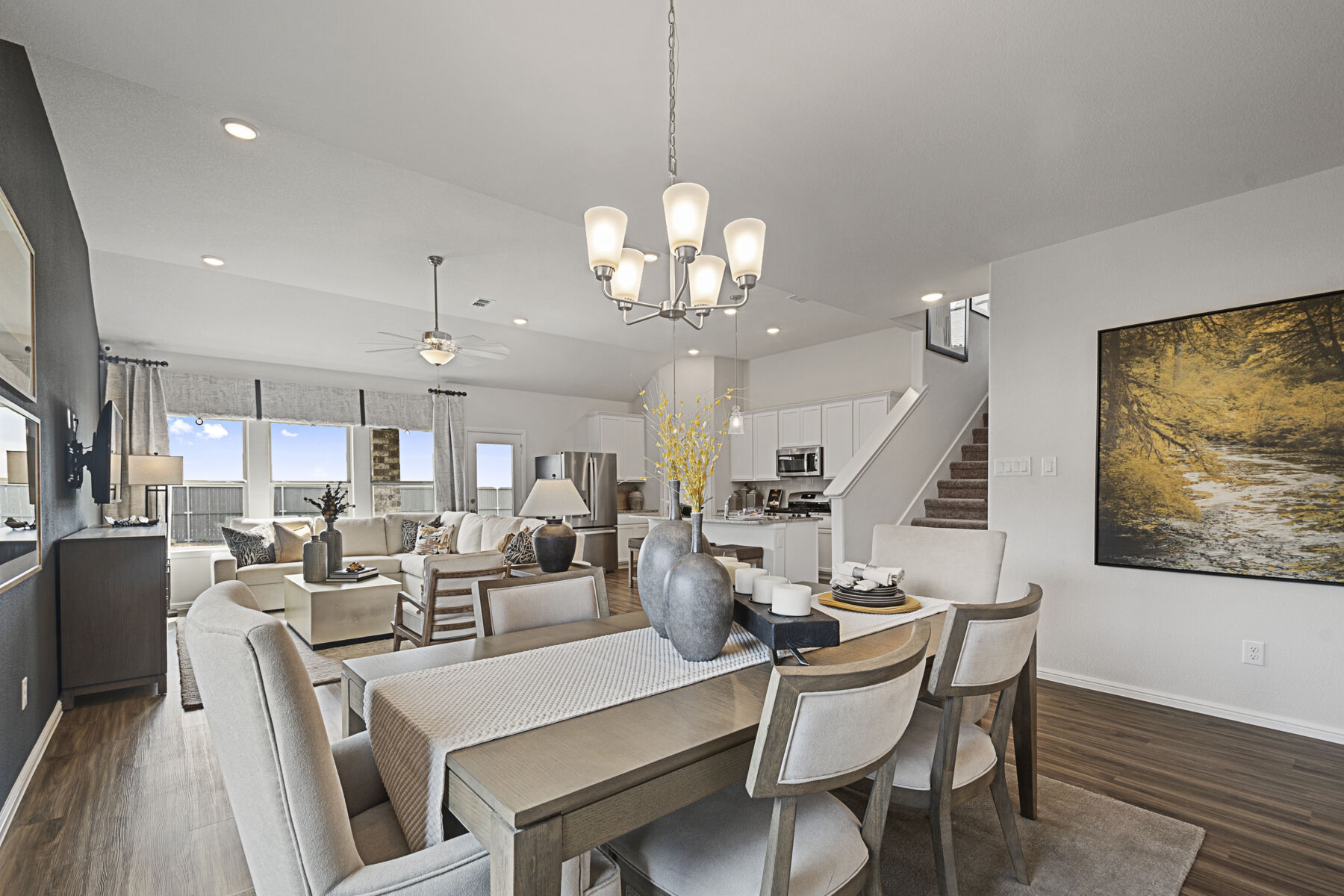 Bright and spacious open-concept living area with combined dining space, modern furnishings, and a view of the staircase in new homes in Goodland TX.