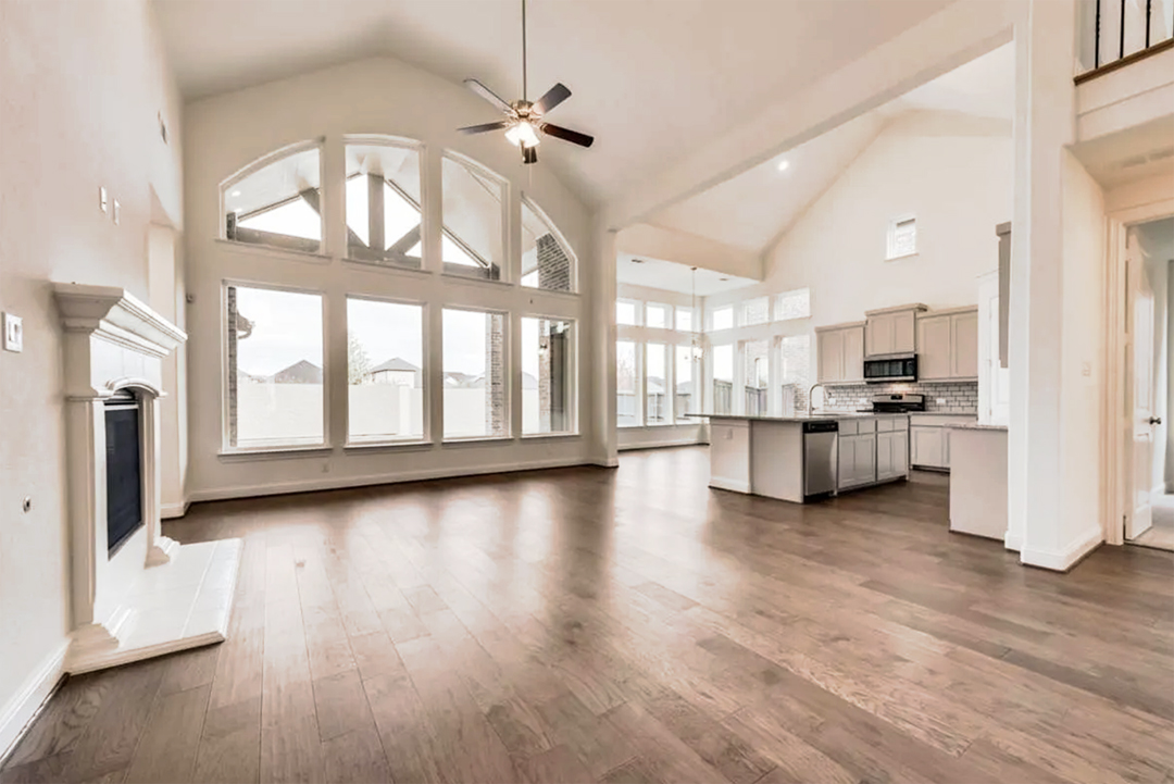 Spacious, modern kitchen in new homes in DFW with high ceilings, large windows, and hardwood floors.