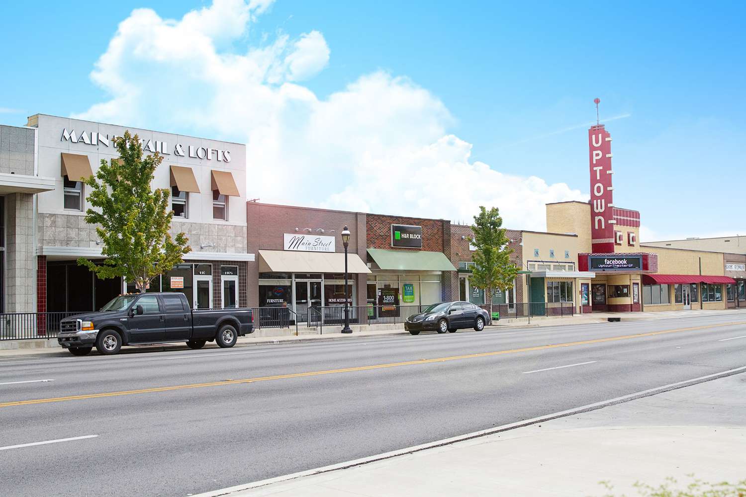 Street view of a small town with various storefronts, including new home builders in Mansfield TX, and a vintage-style theater marquee.