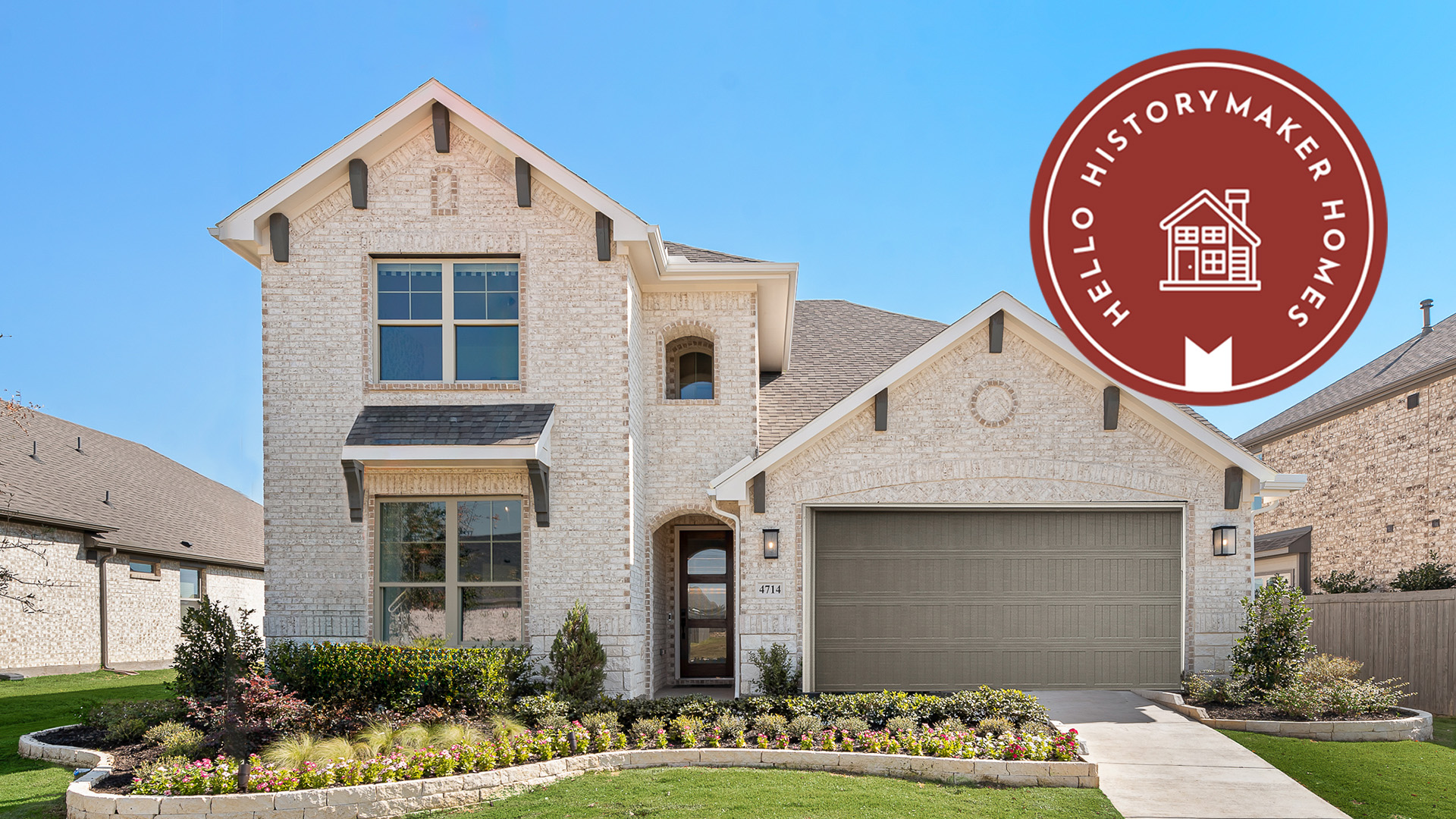 Two-story brick house with a garage, landscaped front garden, and a "Hello HistoryMaker Homes Goodland" logo in the top right corner.