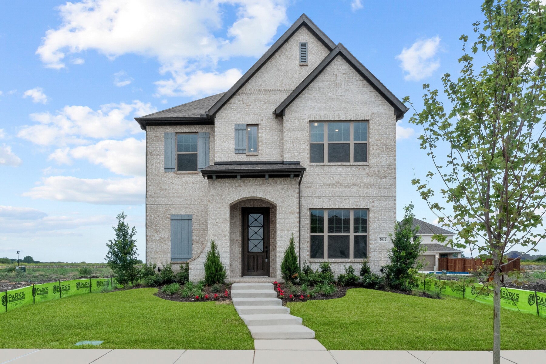 Two-story modern brick house with black trim, large windows, a covered entryway, landscaped front yard, and a concrete walkway—showcasing the style found in model homes Dallas buyers love.